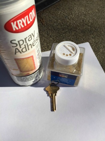 Spray adhesive, glitter and key for DIY ornament supplies.