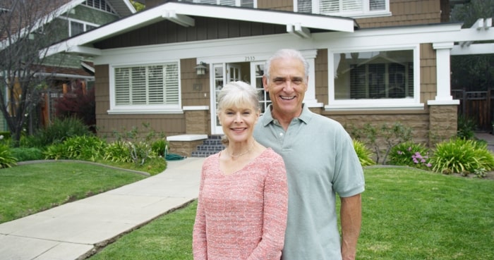 Empty nest couple standing in front of home.