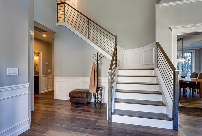 Entryway with wooden stairway and modern railing.