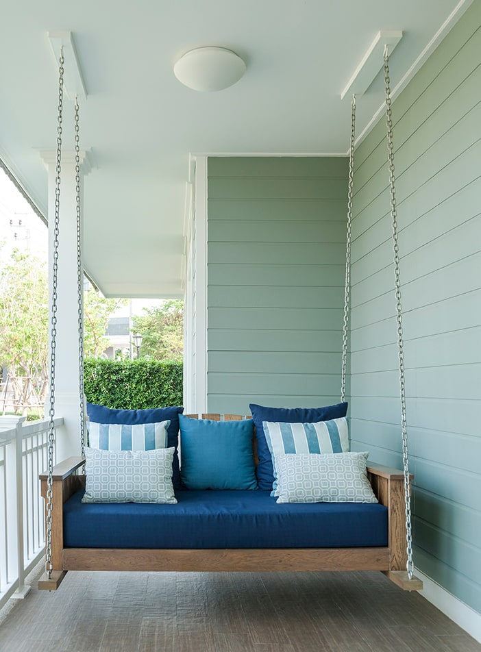 Porch swing with blue cushions.