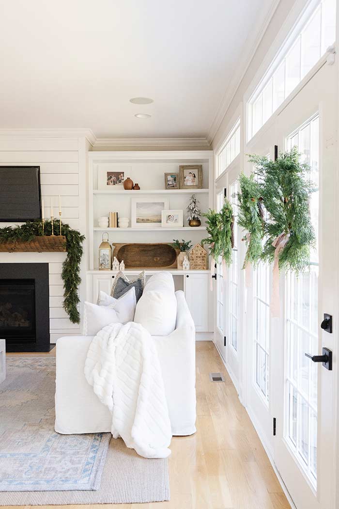 The Coastal Oak living room with indoor wreaths, white couch with blanket.