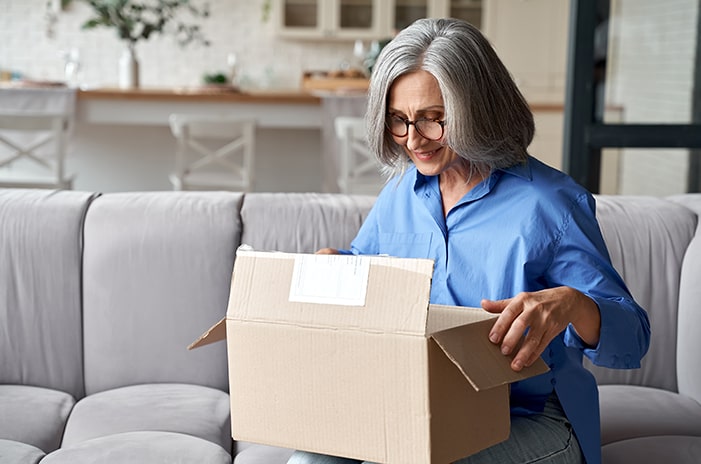 Woman sitting on the couch opening package.