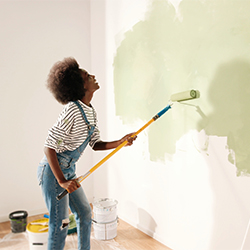 woman painting wall with green paint