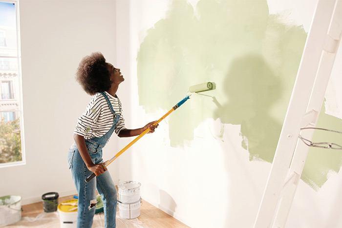 Woman painting wall green.
