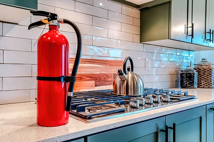 Fire extinguisher on kitchen counter next to stovetop.