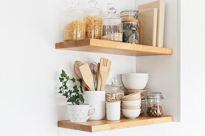 Open kitchen shelves storing dishes, utensils and books.