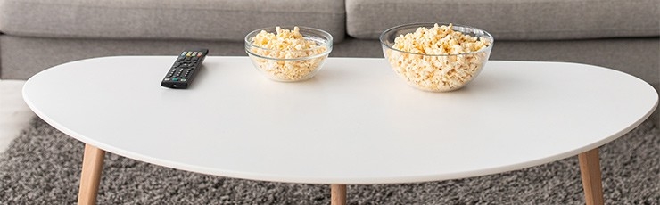 Two bowls of popcorn on white coffee table.