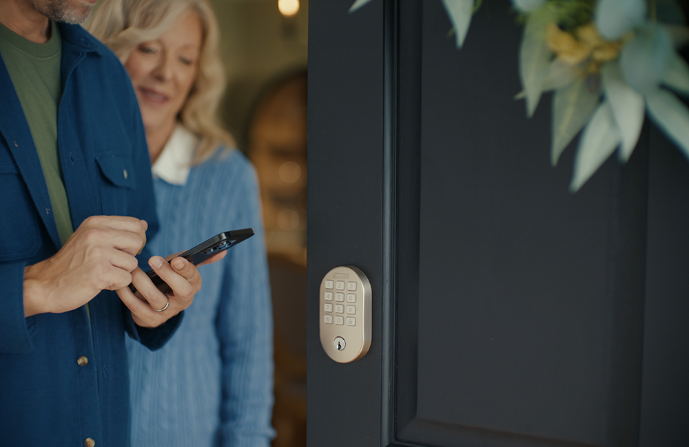 Man giving his elderly mother an access code to unlock the smart lock on his front door.