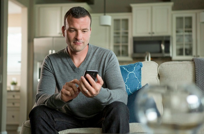 Father sitting on couch looking at smartphone.