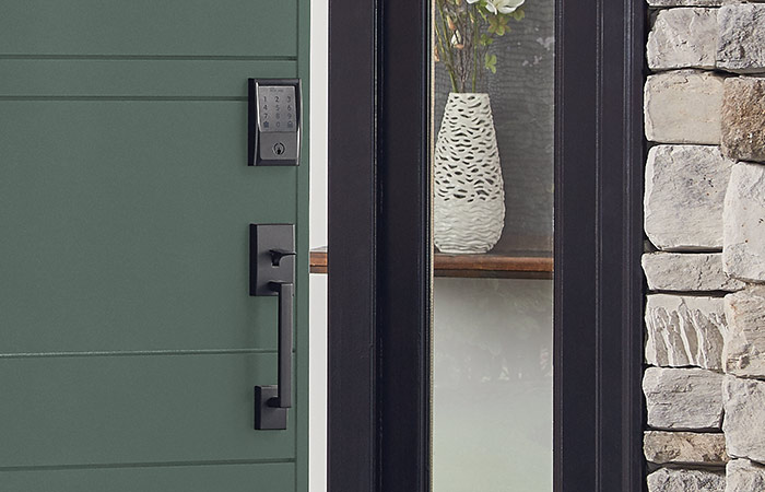 Schlage Encode Smart WiFi Deadbolt in Matte Black on green front door.