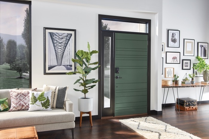 Modern entryway with matte black smart lock on green door.