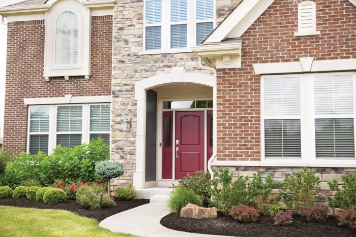 Brick two-story home with red front door.