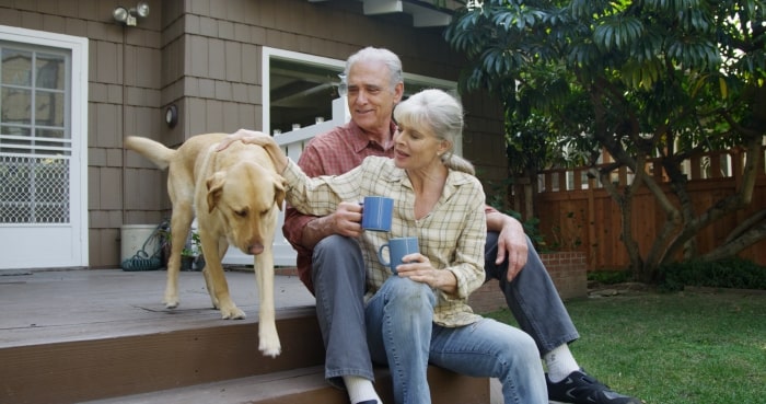 Empty nest couple sitting on back deck with dog.