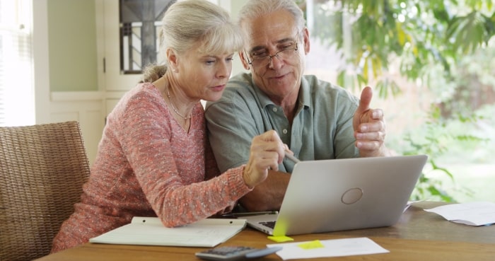 Empty nest couple sitting at laptop planning renovations.