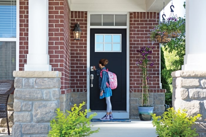 Girl with backpack unlocking Schlage Sense Smart Deadbolt.