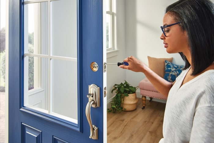 Woman installing new lock on door.