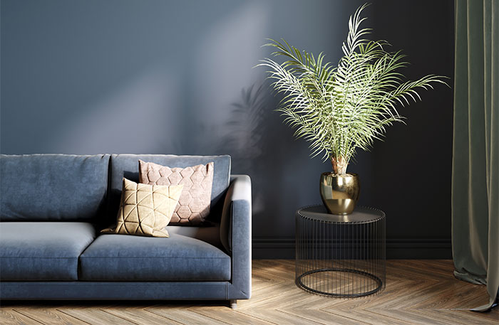 Dark moody living room with pop of color through metallic vase and green plant.