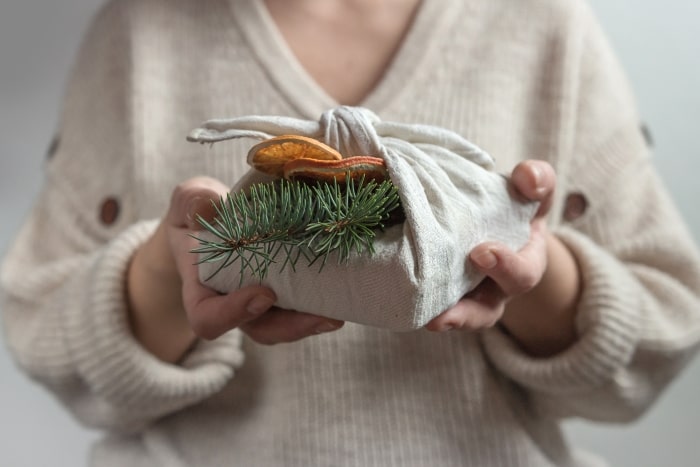 Furoshiki wrapped gift with beige towel and dried oranges.