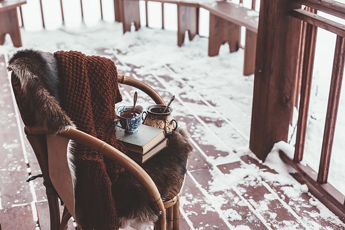Winter porch with cozy chair and warm drinks