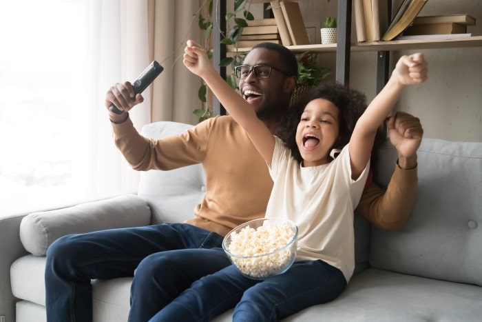 Happy dad and daughter watching football.