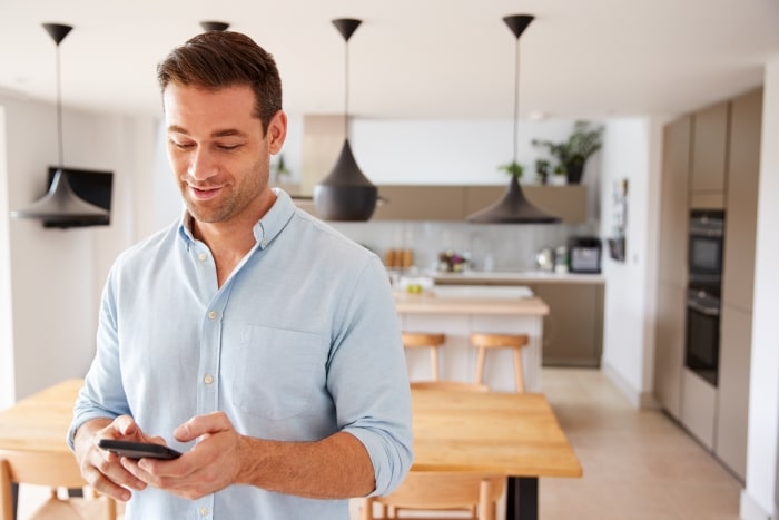 Man holding smartphone in kitchen.