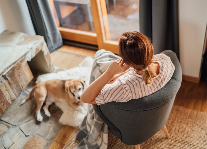 Woman sitting in chair next to dog.