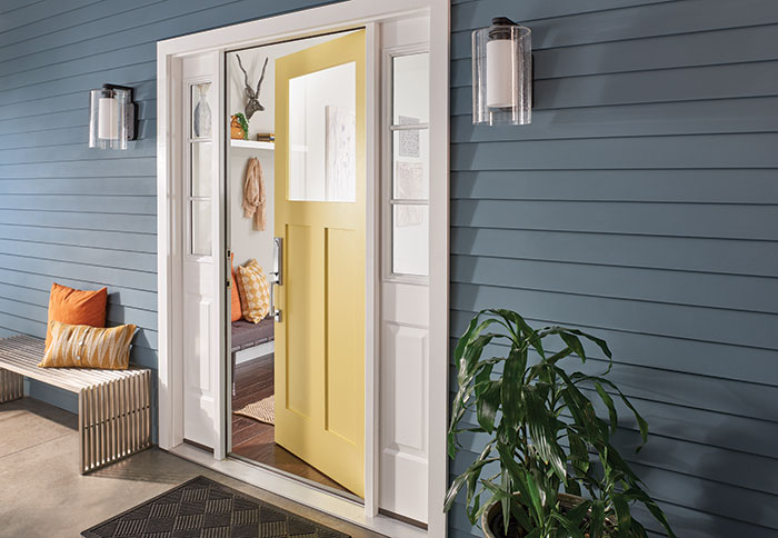 Yellow front door on blue house with Schlage Custom door handle.