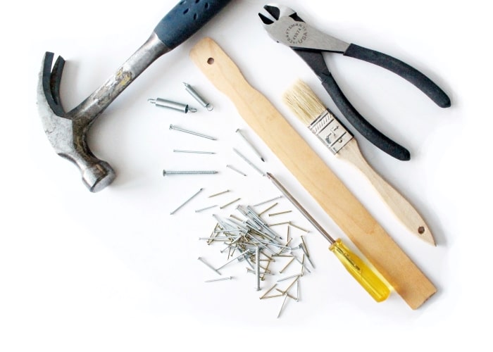 Flatlay of hammer, nails paintbrush.