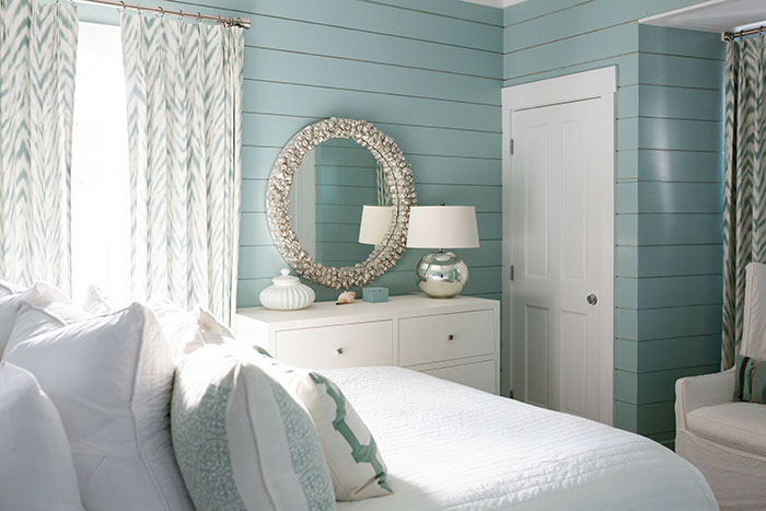 Beach house bedroom with teal shiplap walls.