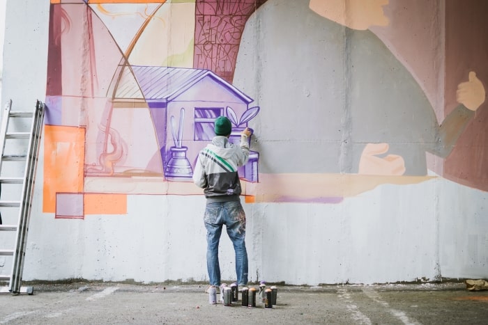 Graffiti artist painting on wall.