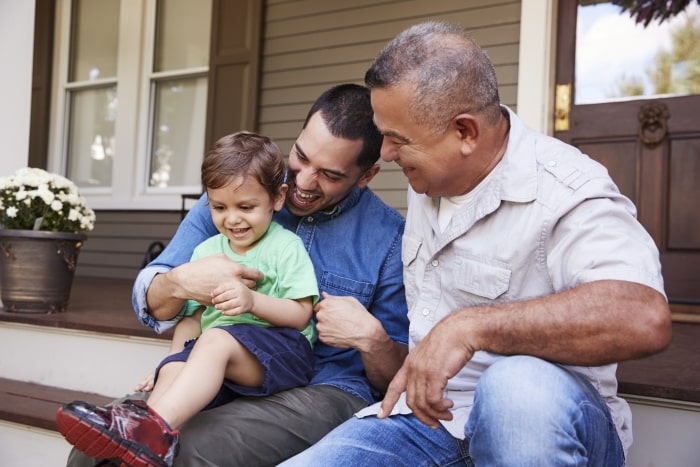 Grandfather, son and grandson sitting on front porch.