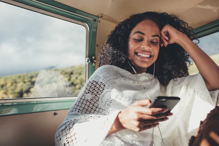 Woman in car listening to playlist on smartphone.