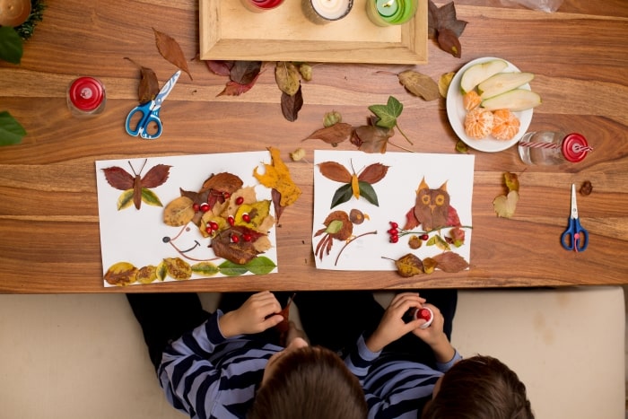 Two kids making fall crafts from leaves.