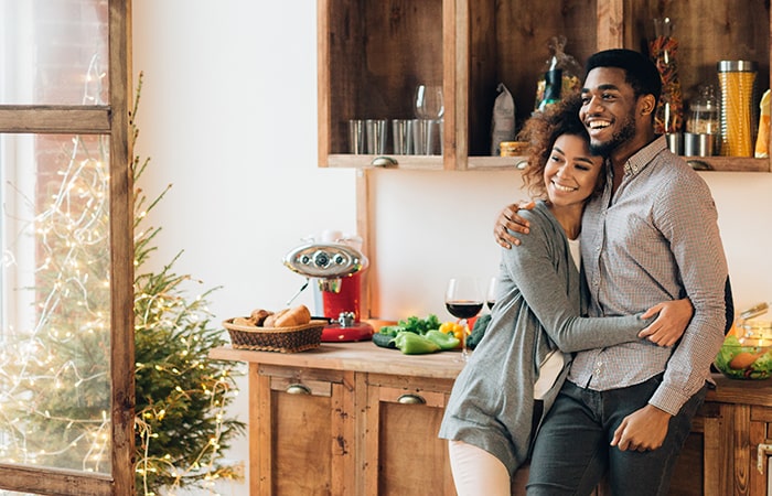 Happy couple standing in kitchen on Christmas morning.