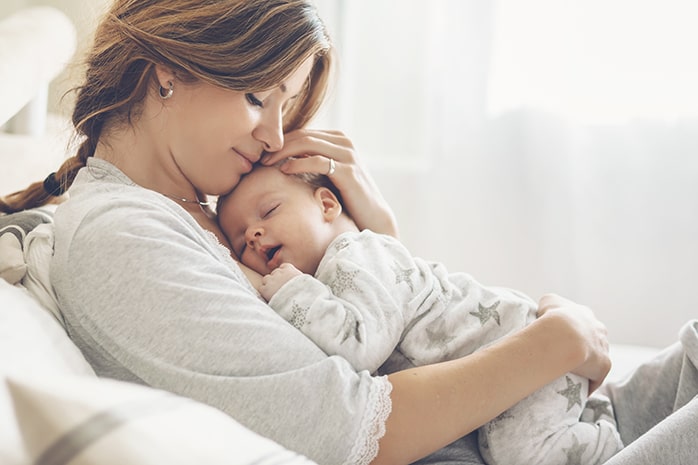 Mom holding sleeping baby on her chest.