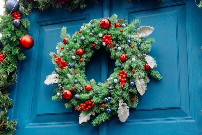 Teal front door with holiday wreath and garland.