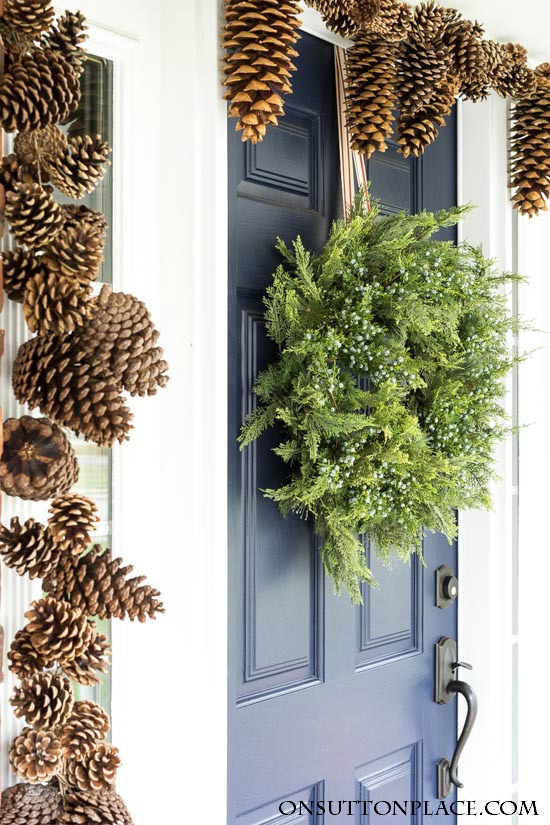 Pine wreath with juniper and pinecone garland around front door.