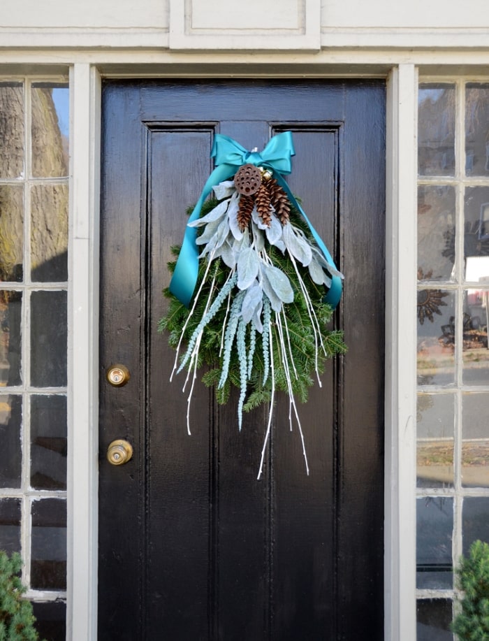 Sprigs of greenery with blue, white and silver accents on front door.