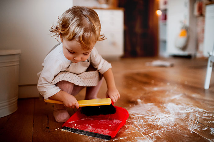 Little girl sweeping the floor.