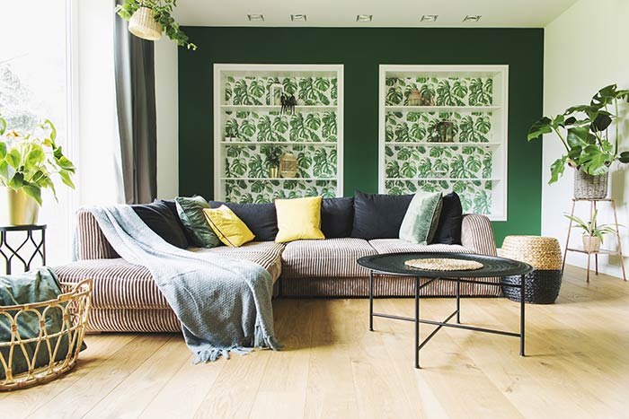 Modern living room with green walls and plant wallpaper.