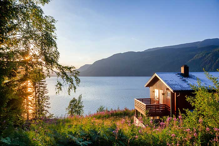 Cabin on lake during sunset.