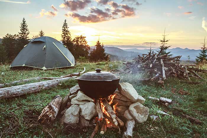 Camp setup with dutch oven over fire and view of mountains.