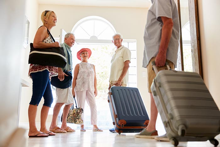 Friends standing in entryway of home with luggage.