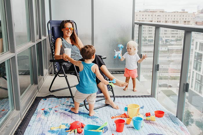 Mom sitting on balcony with two toddlers.
