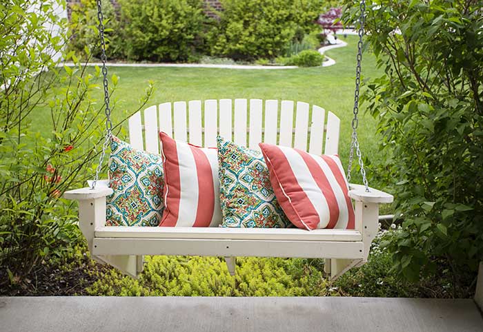 Spring front porch swing with colorful pillows.