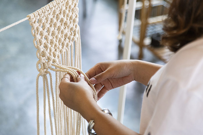 Woman making macrame wall hanging.