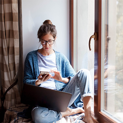 Woman looking at smartphone while sitting next to window