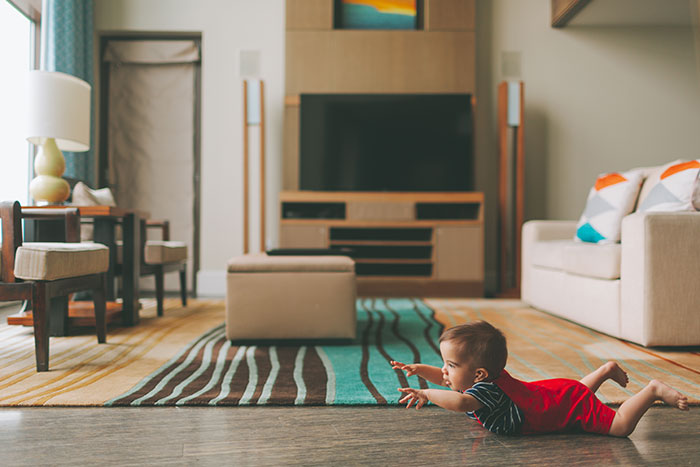 Baby crawling on living room floor.