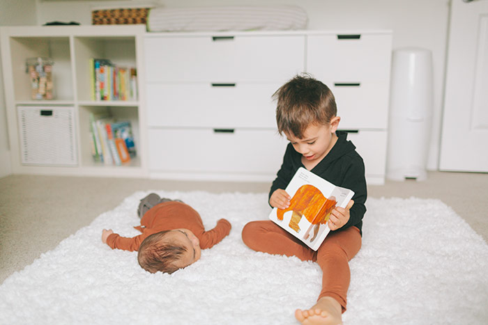 Big brother reading book to baby.