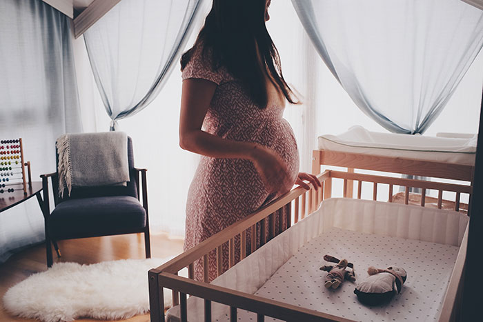 Expectant mother standing in baby's nursery.